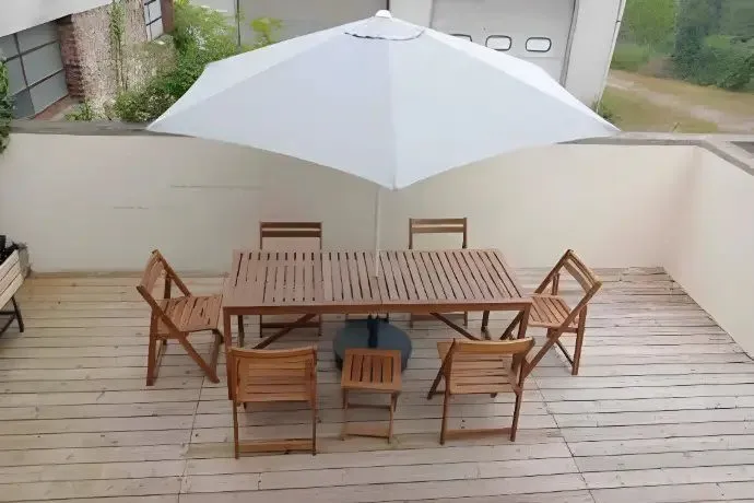 Terrasse en bois avec table, six chaises et parasol.