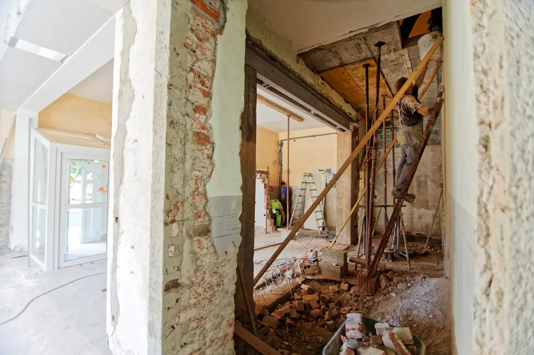 Ouverture d'un mur porteur sur un chantier de rénovation locative : poutre métallique posée, étais et échafaudage en place.