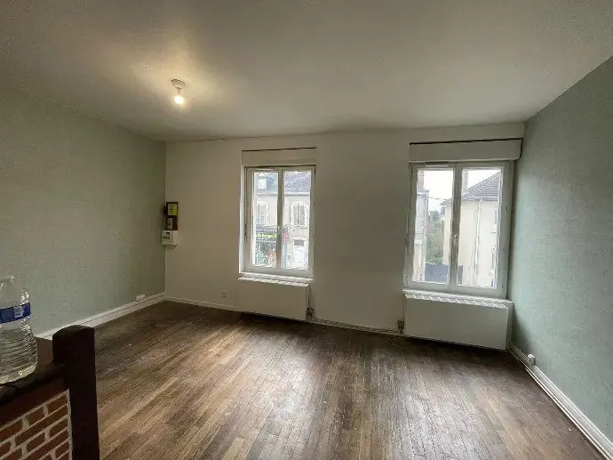 Séjour repeint, parquet clair et deux fenêtres.