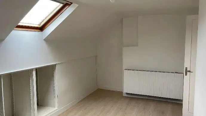 Comble repris en blanc sous rampant, fenêtre de toit et radiateur.