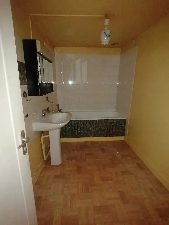 Salle de bains ancienne : baignoire, lavabo sur colonne, murs rose et vert.
