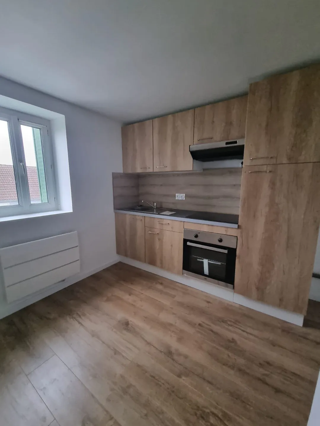 Cuisine neuve toute hauteur en bois clair avec four encastré et crédence.