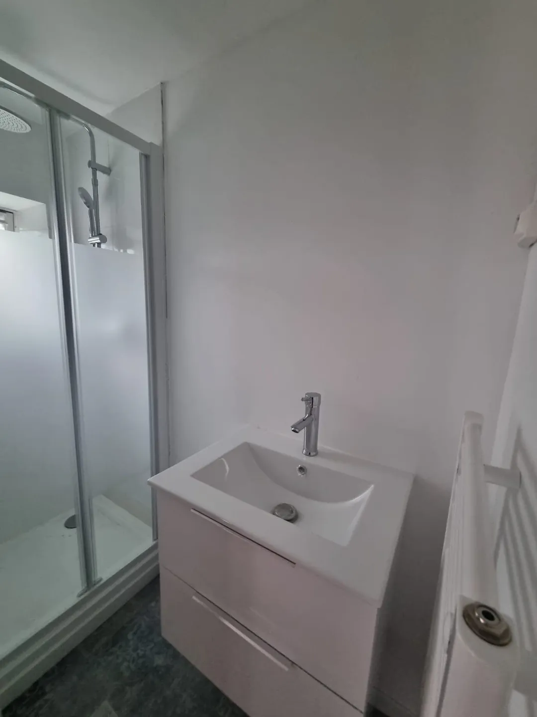 Salle d'eau neuve : cabine de douche, meuble vasque et miroir.