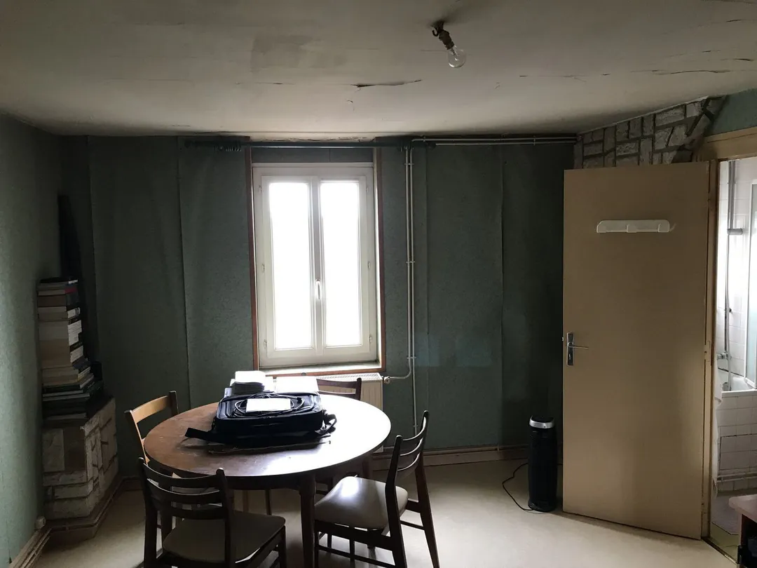 Cuisine aux murs verts avec table ronde, chaises et vieille porte.