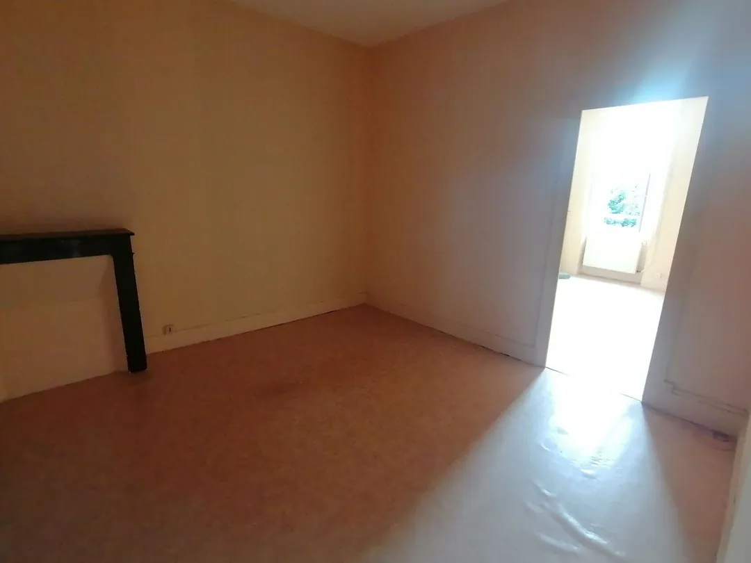 Pièce vide aux murs ocre, porte ouverte sur l'extérieur.