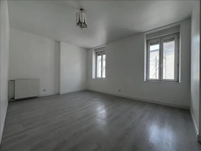 Pièce vide repeinte, sol stratifié gris et deux fenêtres.