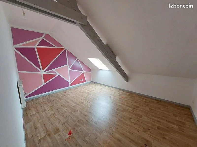 Chambre sous rampant avec fresque murale rose et parquet clair.
