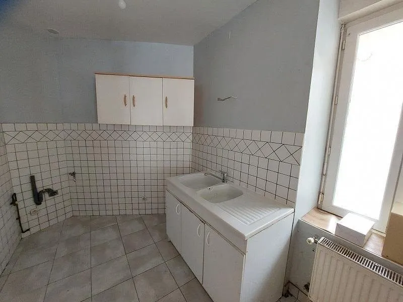 Salle d'eau ancienne avec meubles hauts, lavabo double et carrelage blanc.