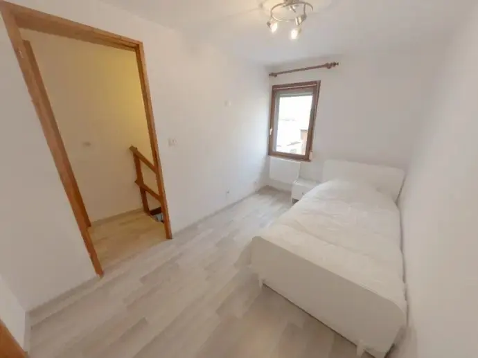 Chambre après travaux : sol clair, mur blanc, couchage et rangement.