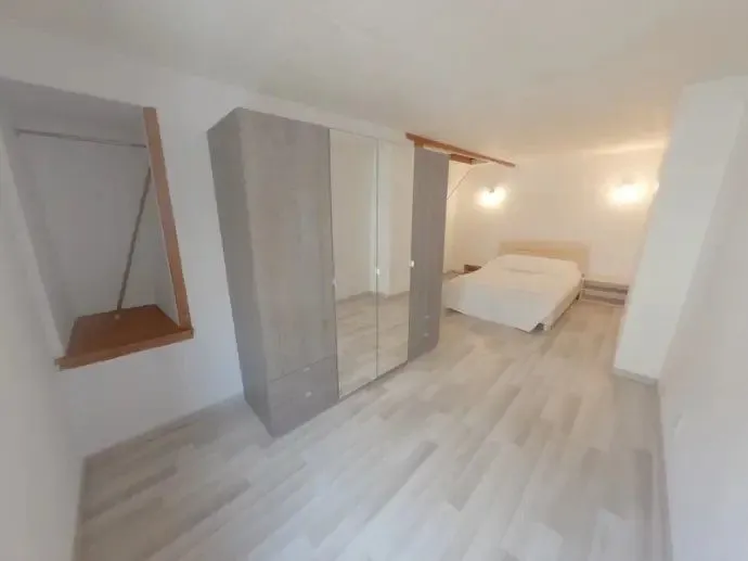 Chambre après travaux avec son dressing, sol clair et escalier attenant.