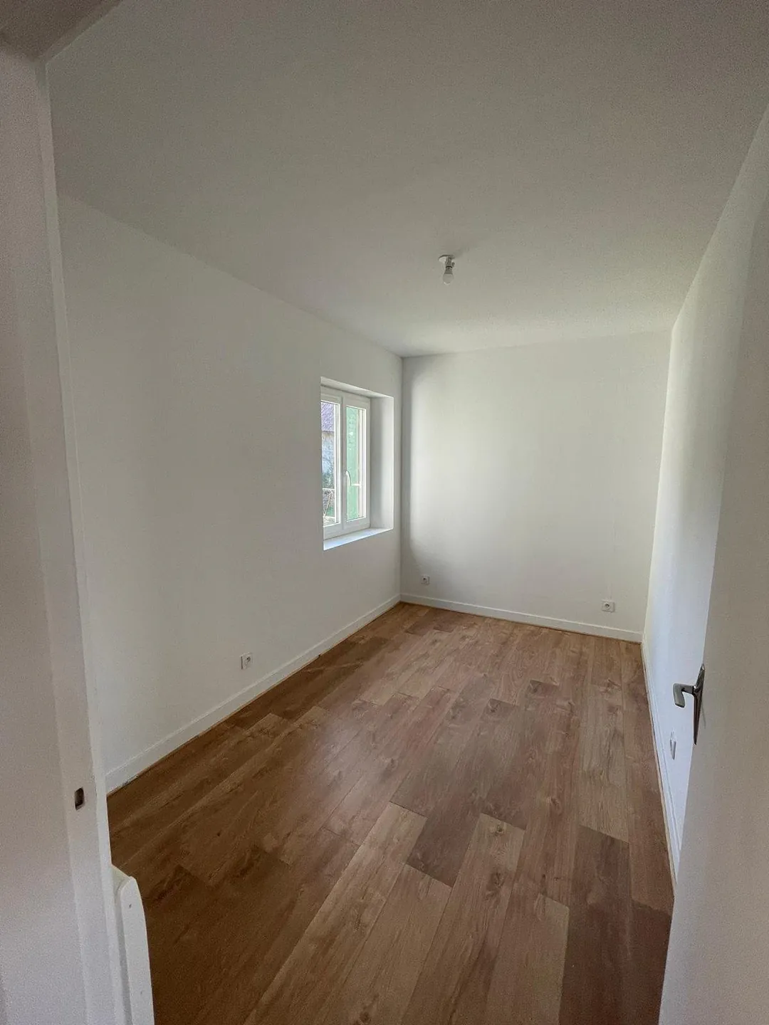Chambre vide après travaux, porte ouverte sur le couloir.