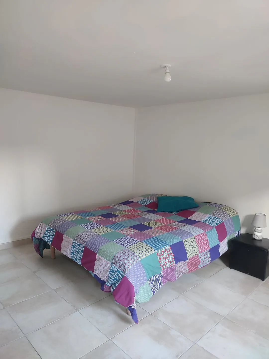 La chambre vue depuis la porte, lit double et chevet.