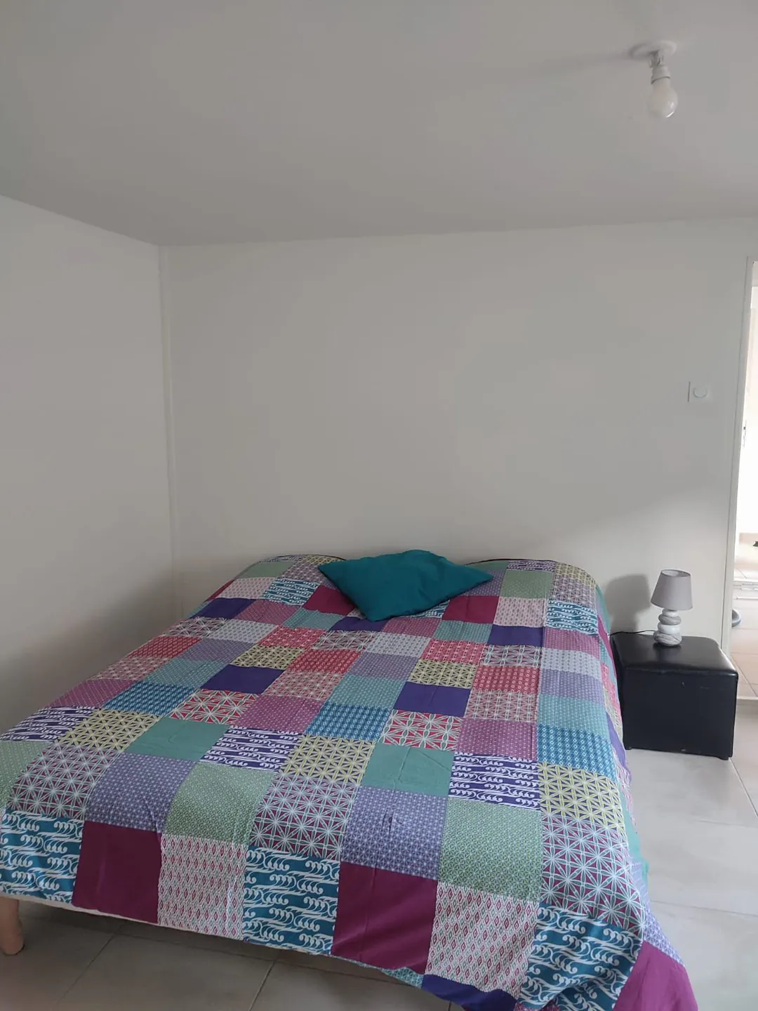 Chambre avec lit double et rangement, fenêtre à gauche.