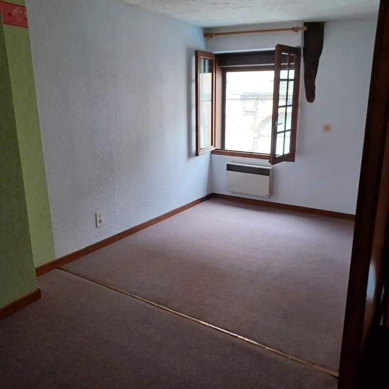 Chambre d'origine vide, moquette bordeaux au sol, fenêtre à petits carreaux.