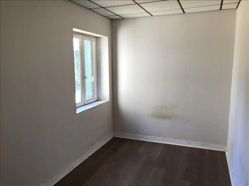 Chambre d'origine, murs blancs et sol stratifié foncé.