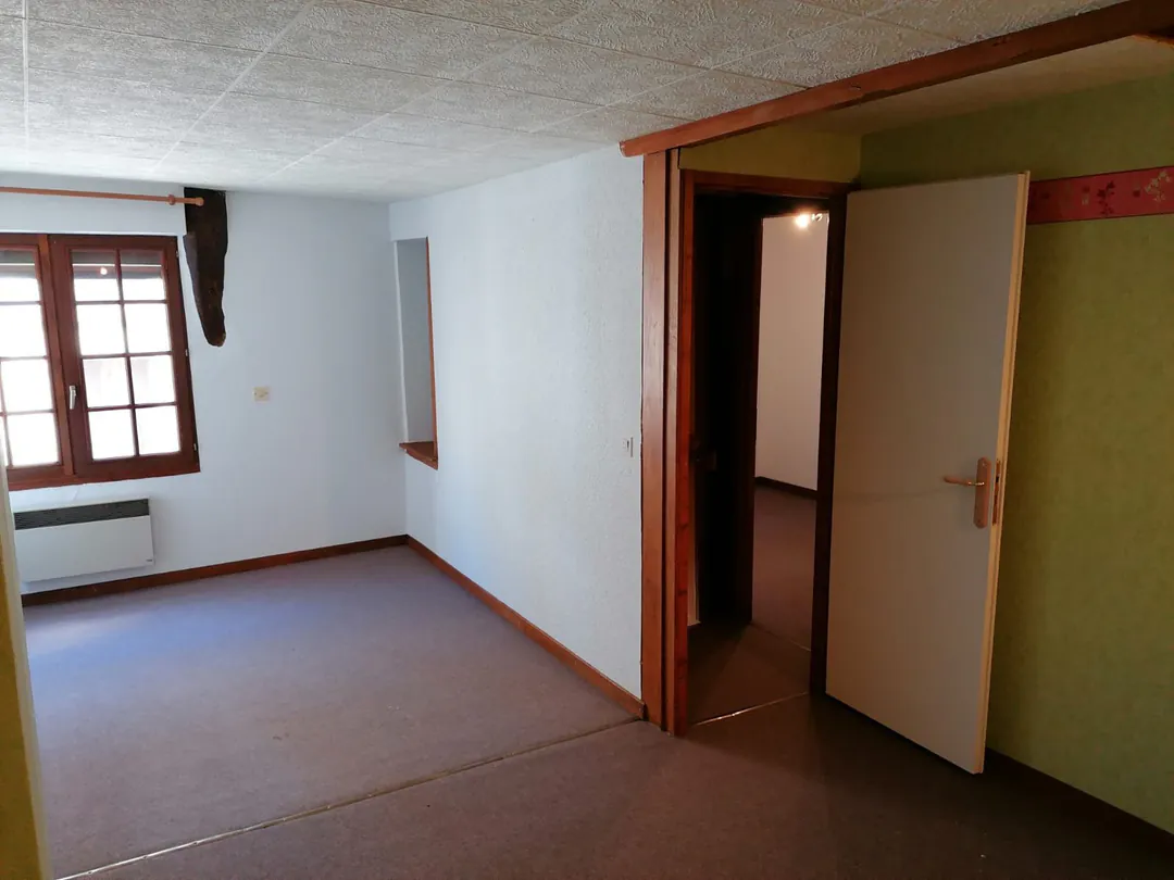 Chambre d'origine, murs vert d'eau et frise rose, portes de placard ouvertes.