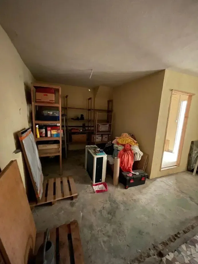 Pièce vidée en cours de dégagement, étagères et affaires contre le mur.