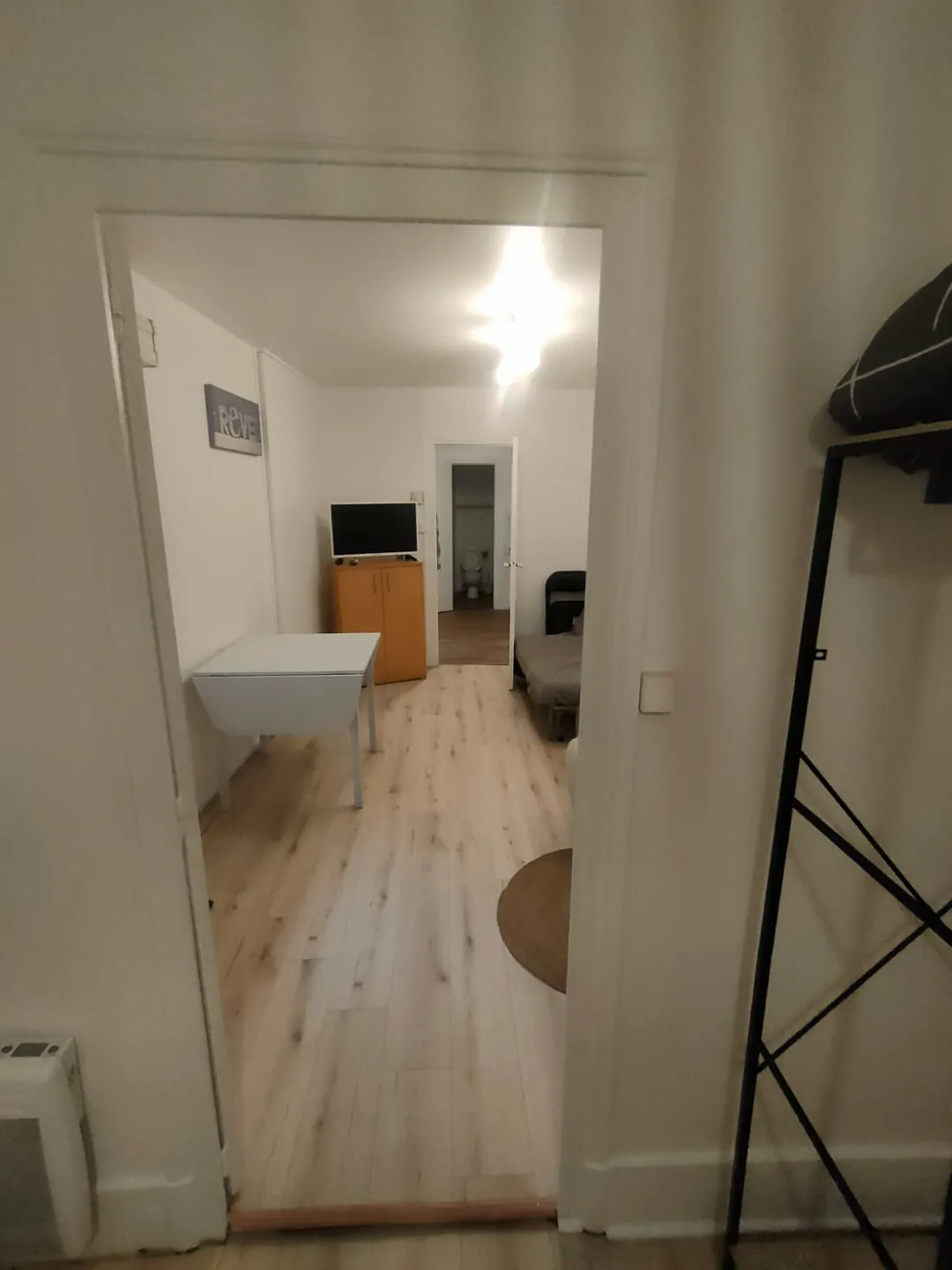 Séjour vu depuis la cuisine, porte ouverte sur la pièce meublée.