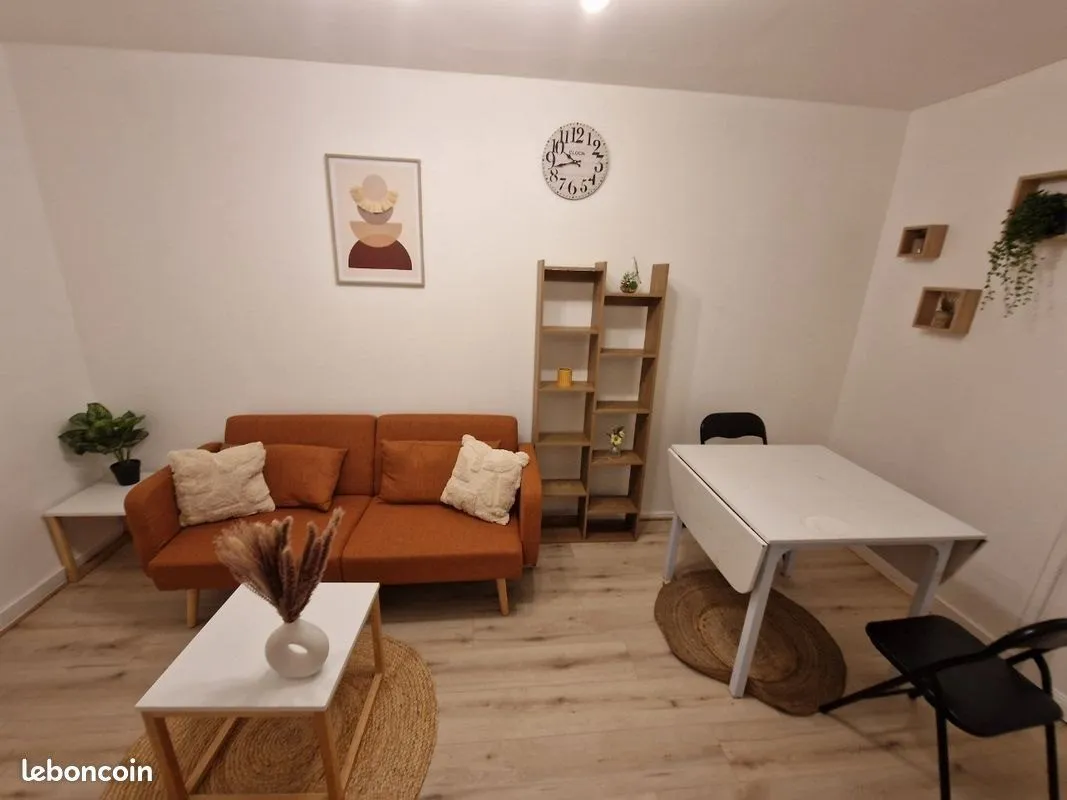 Séjour photographié pour l'annonce : canapé terracotta, table basse, table de repas et décoration murale.