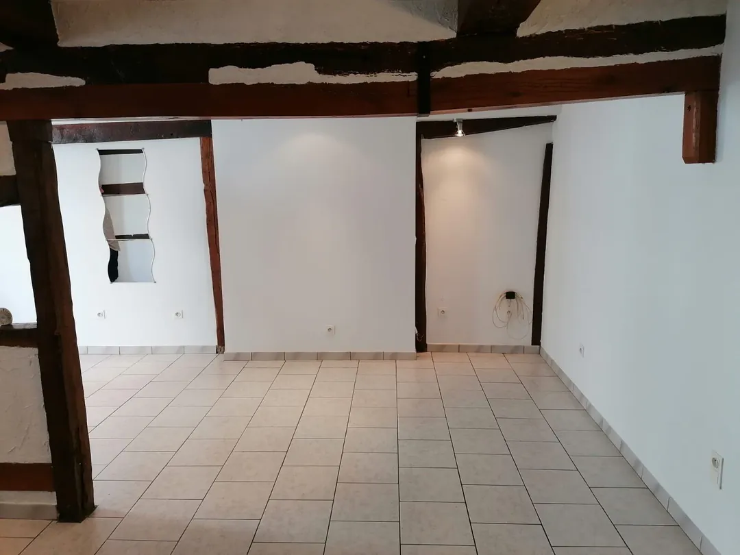 Séjour vide, poutre maîtresse et colombages, rail de spots au plafond.