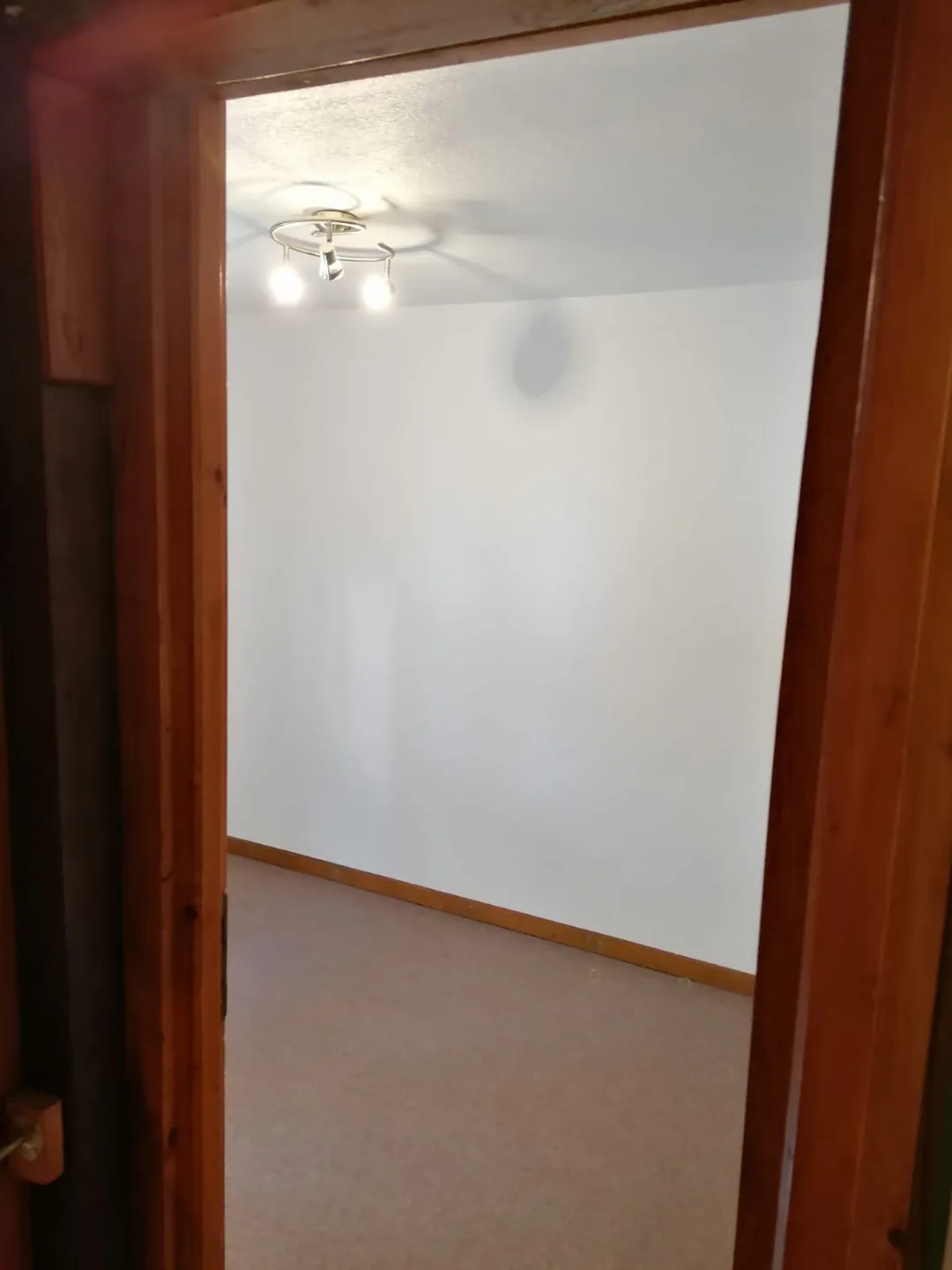 Angle du séjour, mur blanc et poutre apparente.