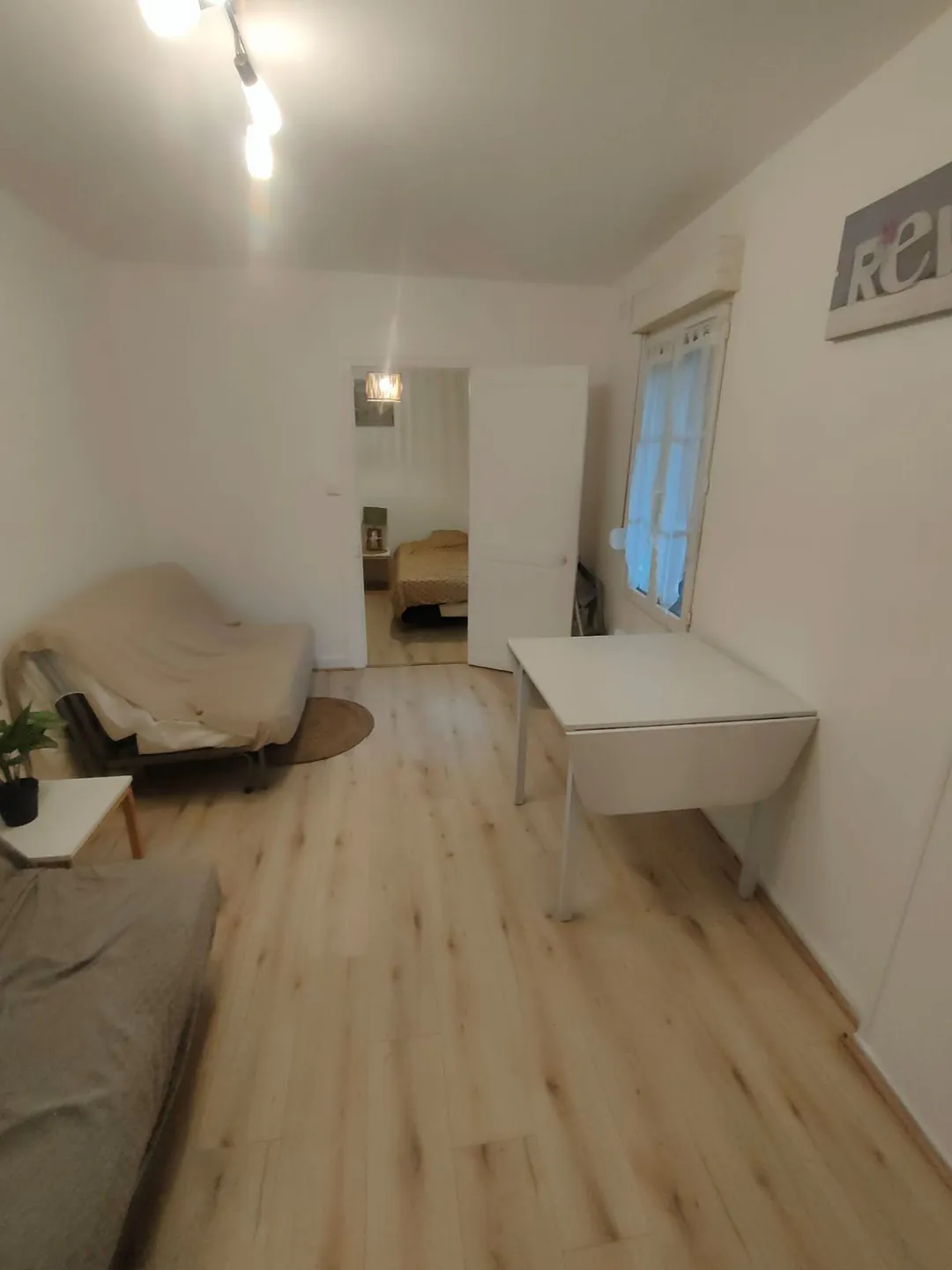Séjour vide, sol neuf posé, matelas et table adossés au mur.