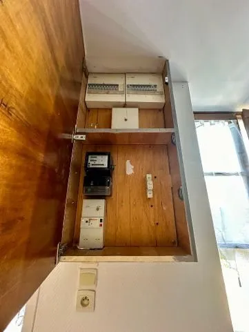 Tableau électrique ancien dans un placard en bois, compteur apparent.