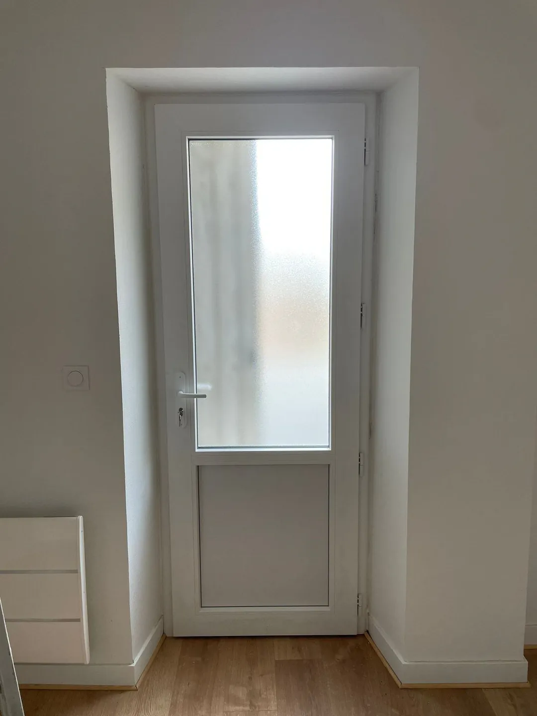 Porte vitrée neuve posée dans son tableau, sol non fini.