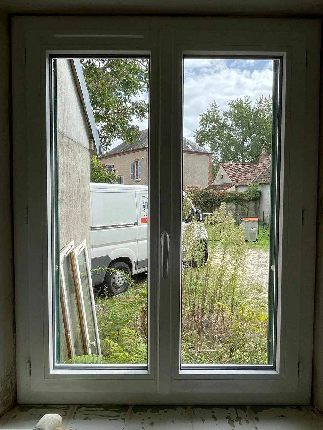 Fenêtre PVC neuve en place, vue sur la cour.