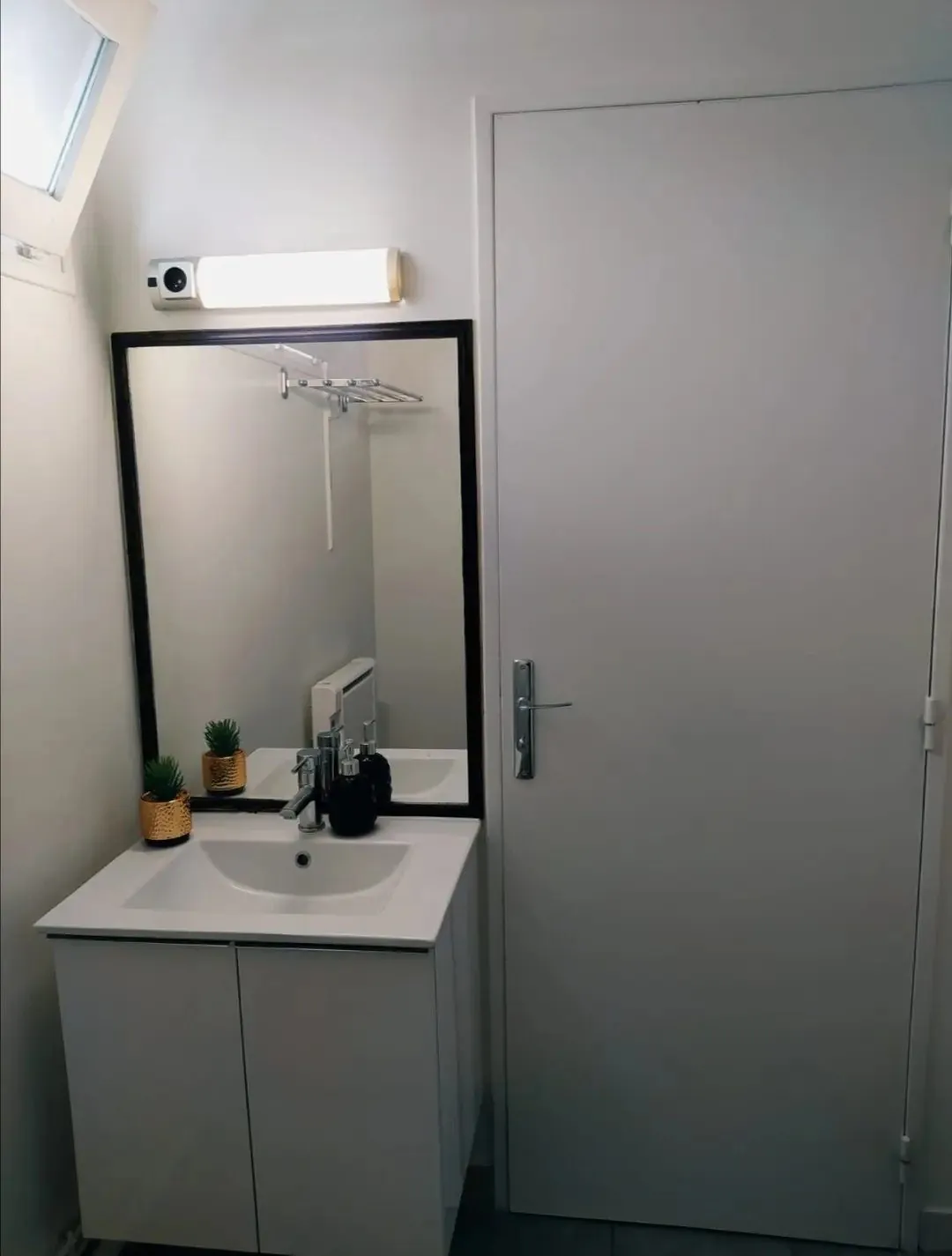 Coin toilette avec meuble vasque blanc, miroir et applique.