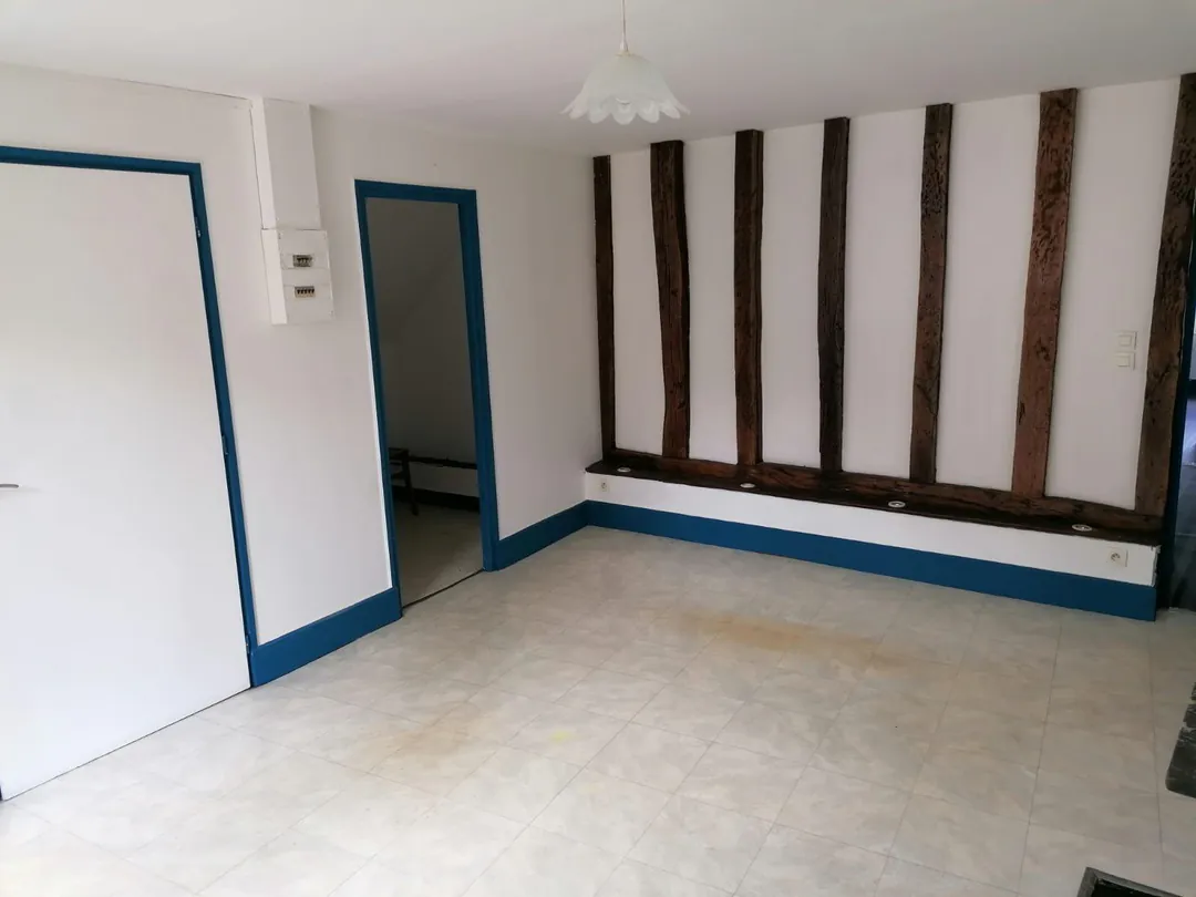 Pièce vide aux colombages apparents et plinthes bleues.