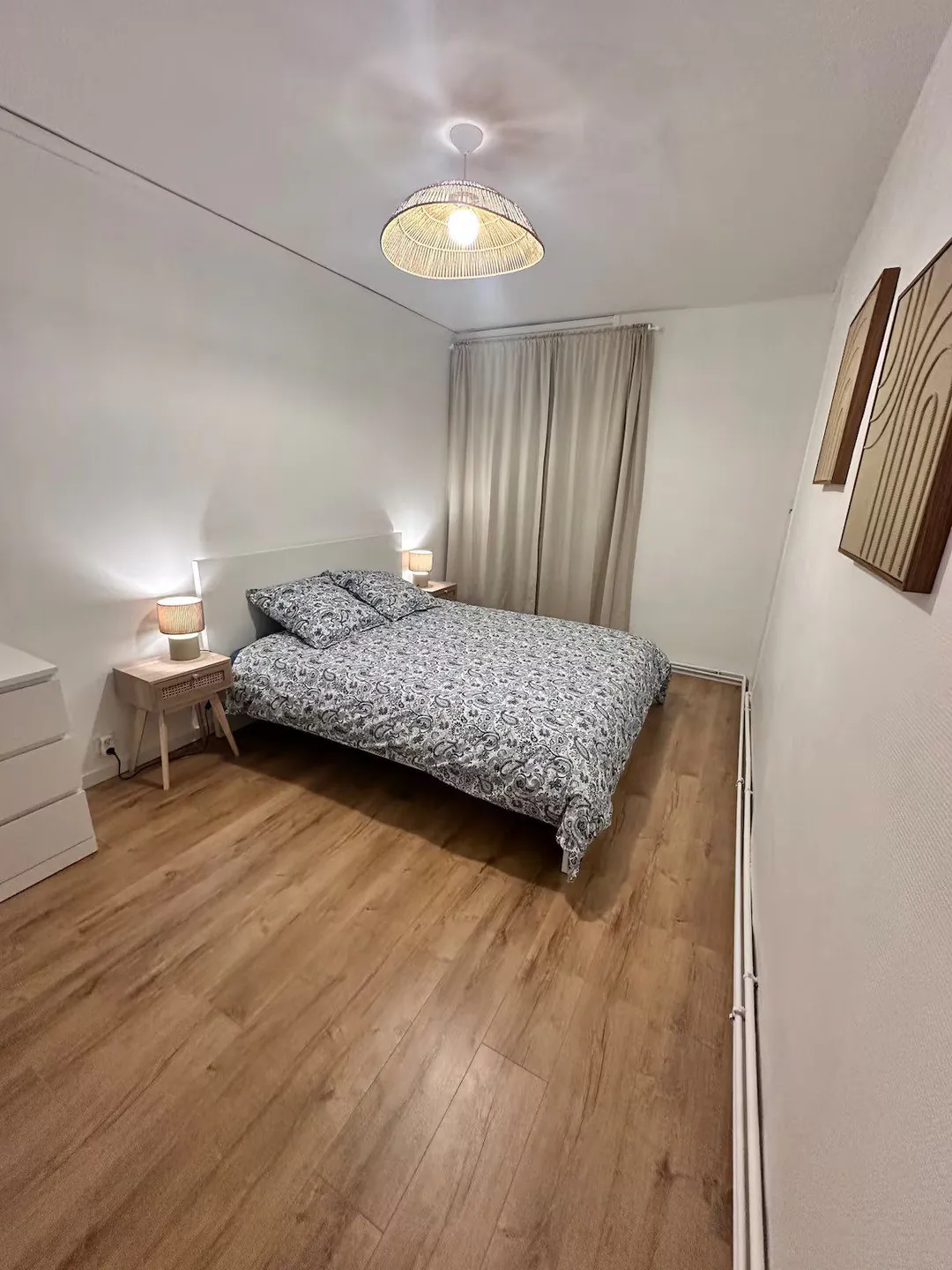 Chambre avec lit double, tables de chevet et rideaux.