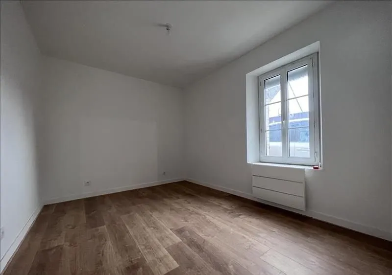 Pièce vide après travaux, murs blancs et sol stratifié.