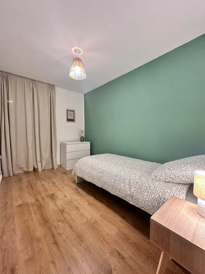 Chambre avec mur vert d'eau, lit simple et bureau.