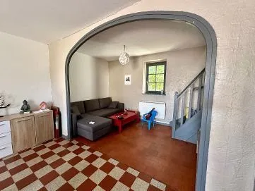 Séjour sous une arche maçonnée, canapé et carrelage rouge et blanc en damier.