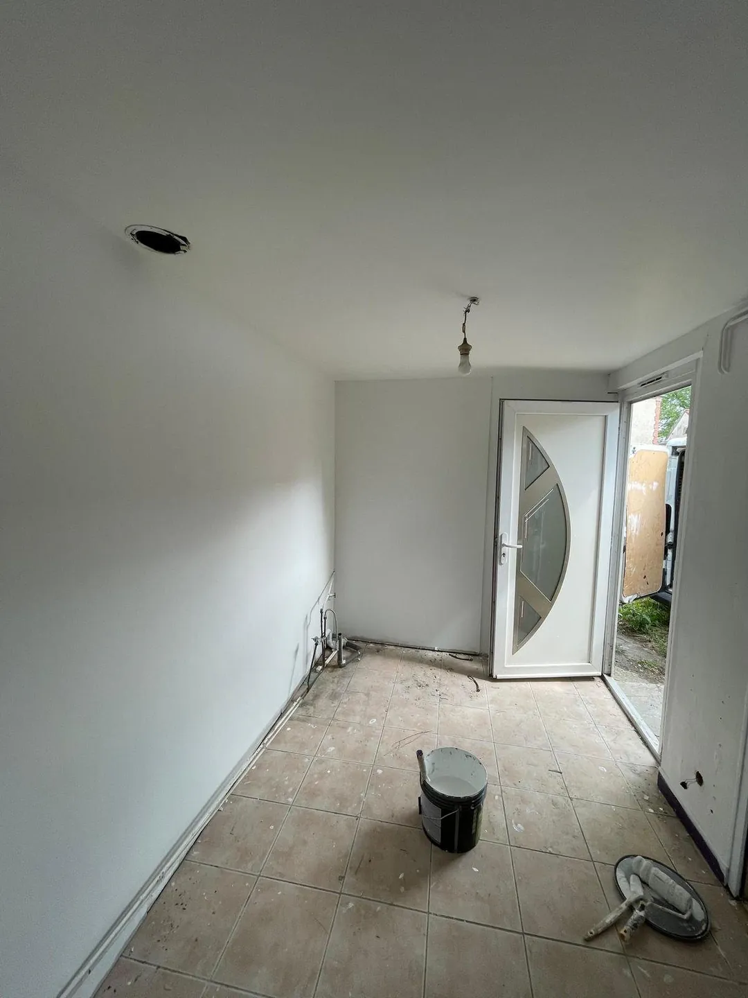 Le salon en chantier, murs poncés et seau de peinture au sol.