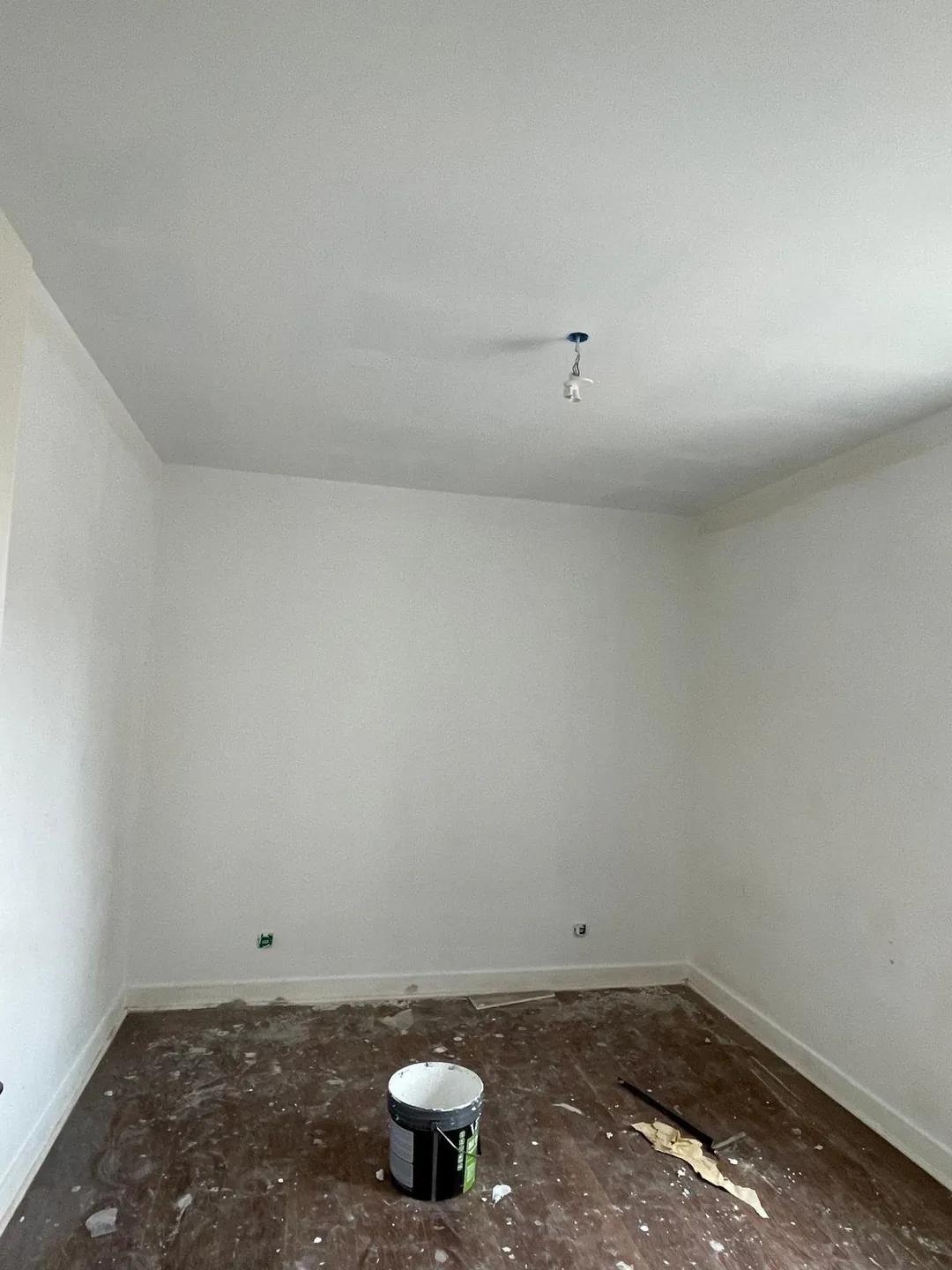 Pièce en cours de finition, sol encore nu et murs blancs.